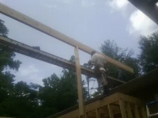 Carpenter setting a ridge beam over a new addition frame — Ice Dam Removal by Roofing Brothers in Farmingville