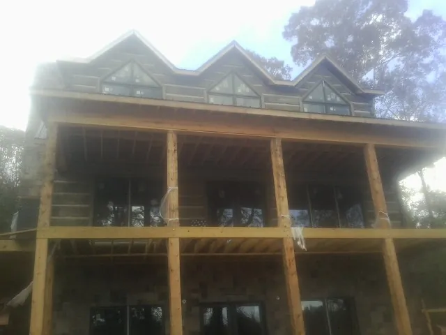 Dormers and porch framing on a large log home under construction — Roof Coating work by our crew in Farmingville