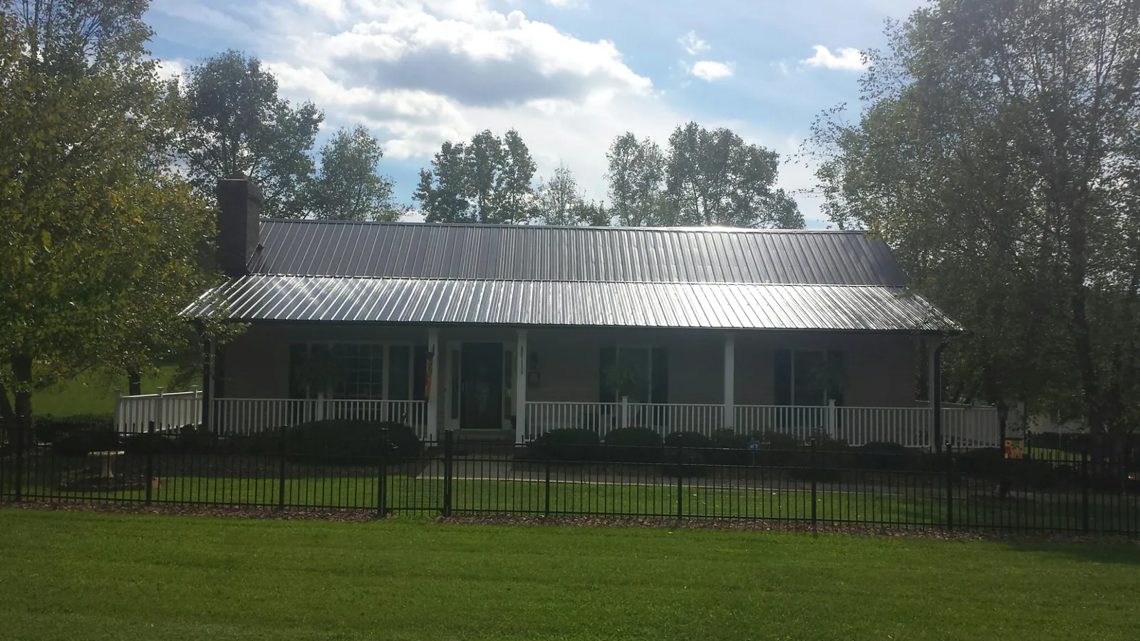 Gray metal roof on a brick ranch with a full width front porch — Gutter Guard Installation work by our crew in Farmingville