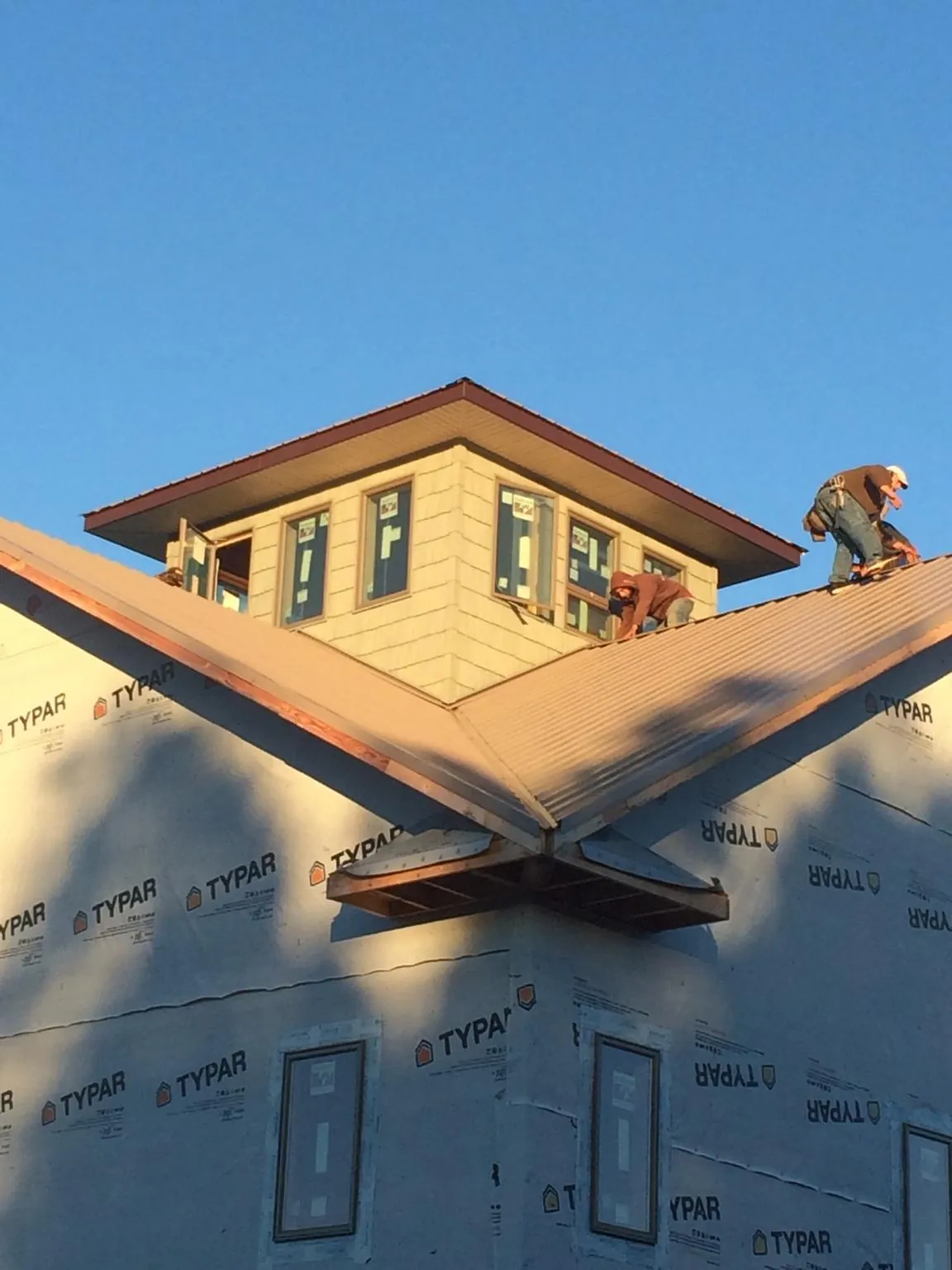 Roofers working around a rooftop cupola on a new metal roof at sunset — Roof Waterproofing in Farmingville by Roofing Brothers
